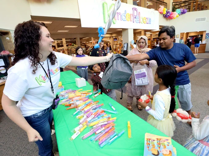 Families receiving backpack full of school materials from staff at Kinderpalooza event at the Tuscaloosa Public Library.