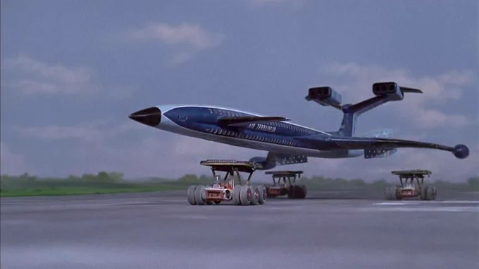 Model of a futuristic plane about to land on three trucks.