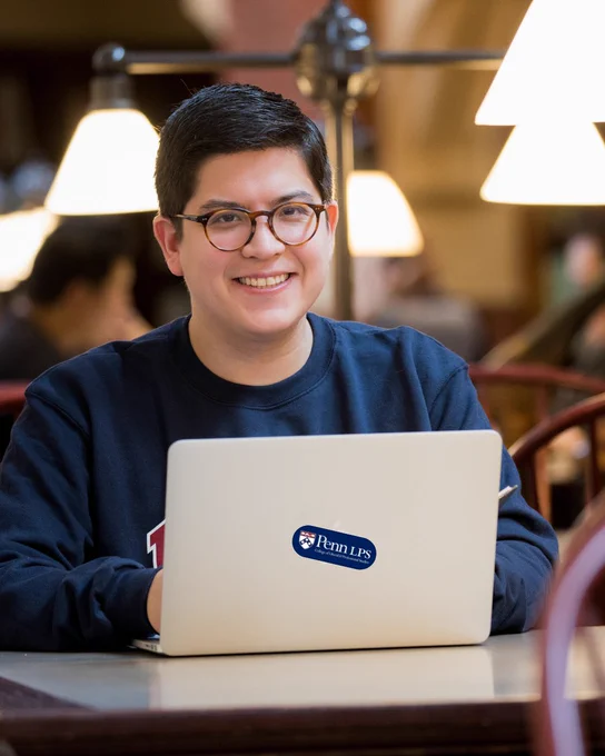 Student smiling sitting in front of a laptop. 