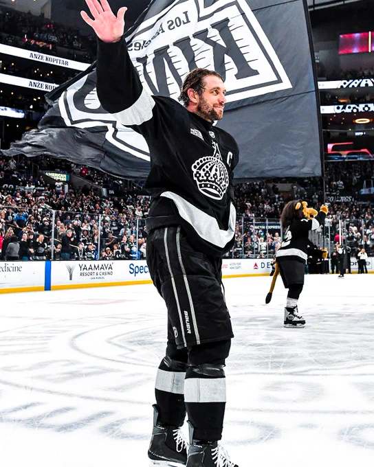 Anze Kopitar waves to the fans on ice in a Kings uniform. 