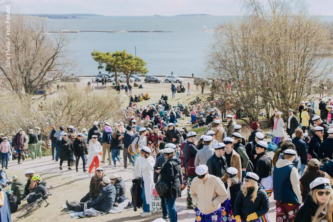 May Day celebrations in a park. A lot of people wearing high school hats.