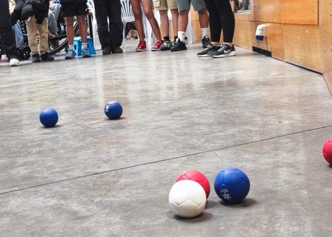 En la imagen aparece un grupo de alumnos y alumnas lanzando unas bolas del juego de la bocha.