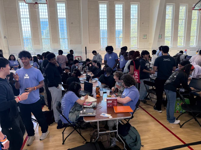 Students gather around long tables filled with laptops and notebooks during 2026 Bitcamp.