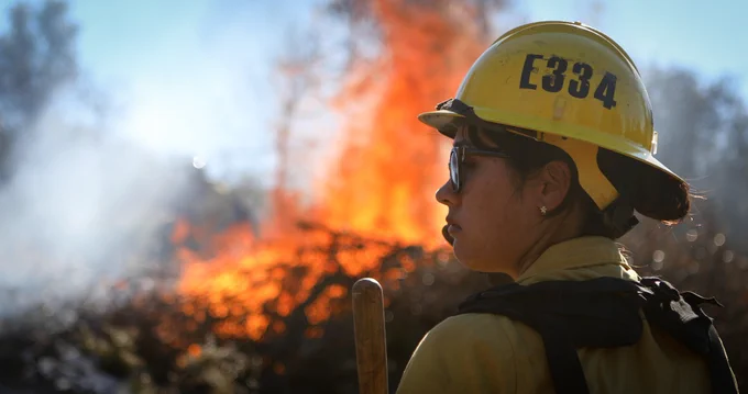 A photo of a Firefighter standing by and monitors a pile burn on the Cleveland National Forest.