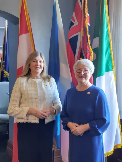 Alison Johnstone (left) pictured with The Hon Edith Dumont, Lieutenant Governor of Ontario, in front of flags.