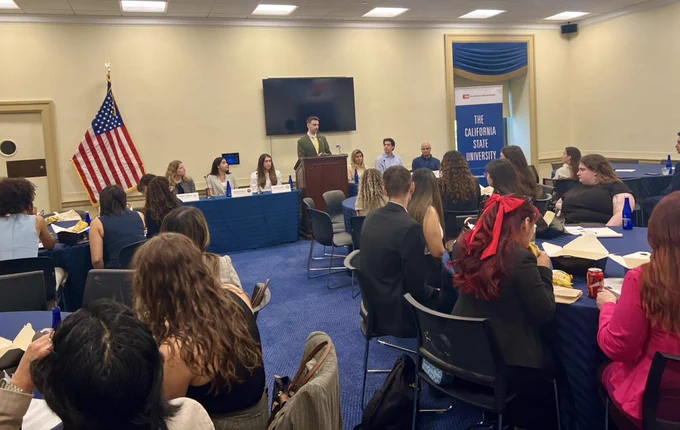 Wide shot of room filled with students listening to a panel.