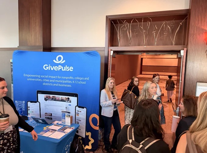Conference hall showing attendees gathered around the GivePulse booth at SERC