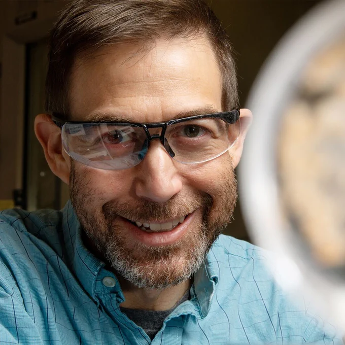 Photo of researcher Scott Baker in a laboratory setting, smiling at the camera.