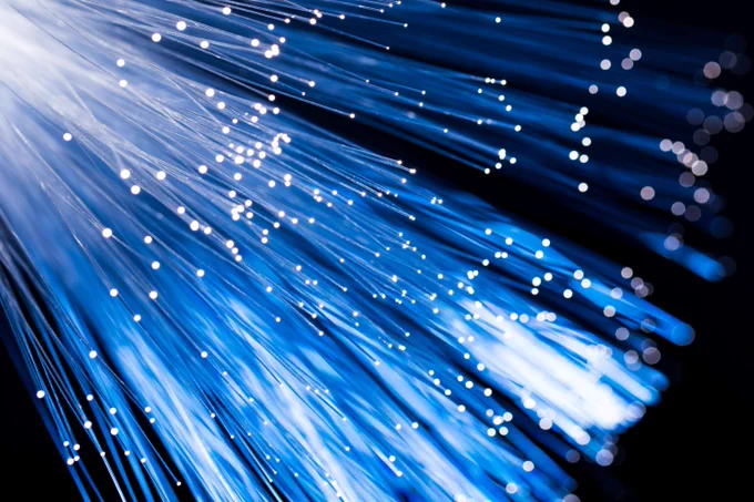 Close-up of blue fiber optic cables emitting bright white light against a dark background.
