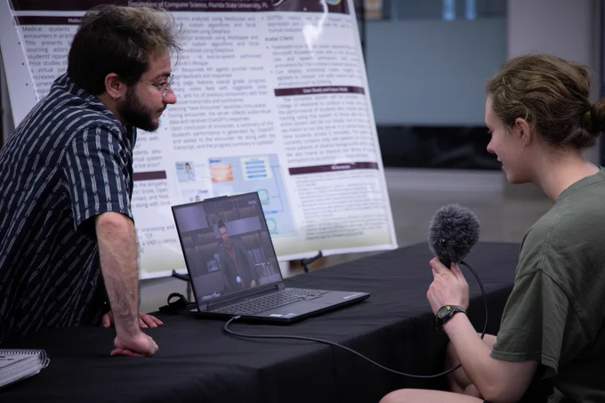 Two attendees conversing and testing out a computer program.