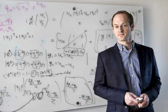 Andrew Childs stands against whiteboard of equations