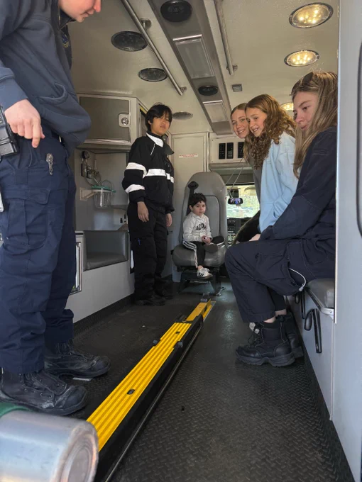 Several people sitting in the back of an emergency medical services vehicle, with medical supplies and equipment visible.