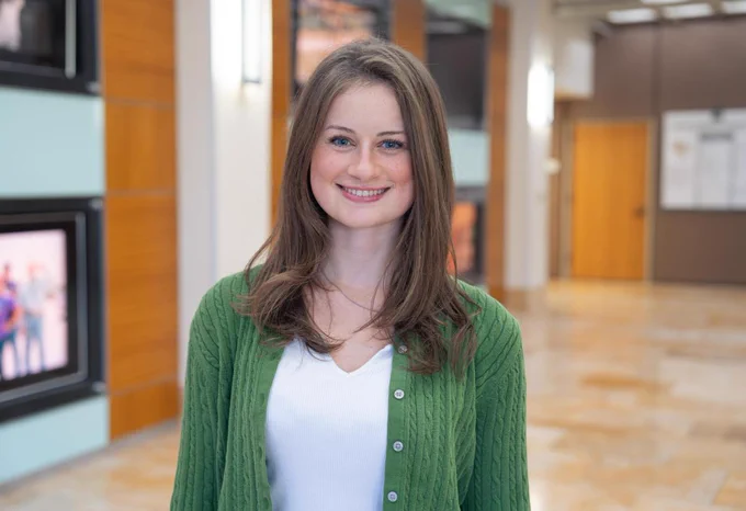 The photo is a portrait of junior mechanical engineering student Savannah Smith in a green sweater. Photo by Makenna Morgan. 