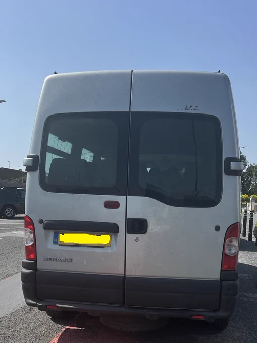 Rear view of a silver Renault van parked in a sunny outdoor lot with tinted windows and a visible license plate.