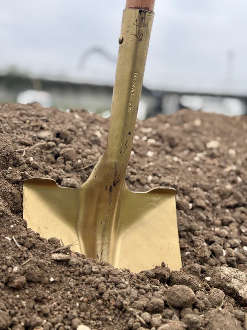 close up of a golden shovel in a pile of dirt
