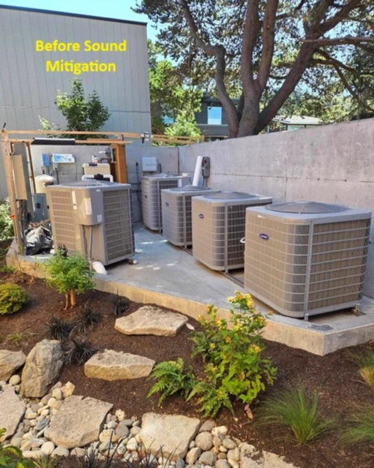 A concrete area contains several Carrier air conditioning units placed in a row. The surroundings feature a landscaped garden with rocks and plants. A wall and trees are in the background. Text at the top reads "Before Sound Mitigation."
