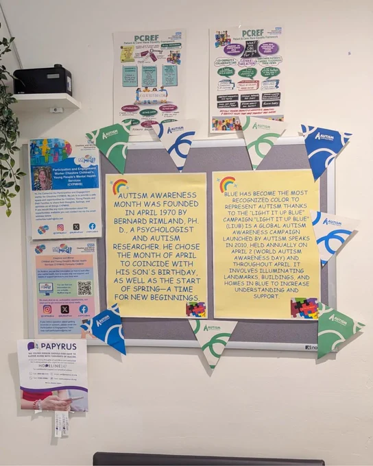 A picture of a noticeboard in the Kingsley Resource Centre, Ellesmere Port, waiting room. On the noticeboard there is Autism Acceptance Month bunting, pictures of puzzle pieces and infinity symbols, and printed information about Autism Awareness Month.