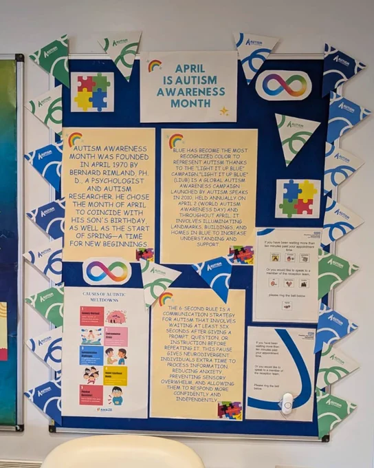 A picture of a noticeboard in the Crook Lane, Winsford, waiting room. On the noticeboard there is Autism Acceptance Month bunting, pictures of puzzle pieces and infinity symbols, and printed information about Autism Awareness Month.