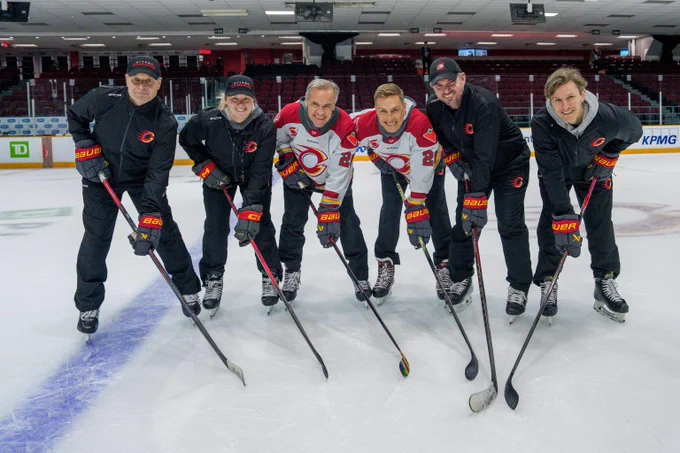 Le premier ministre Mark Carney et le président de la Finlande, Alexander Stubb, posent sur la glace aux côtés de membres de la Charge d’Ottawa; ils sont tous debout, penchés vers l’avant, en appui sur leurs bâtons de hockey.