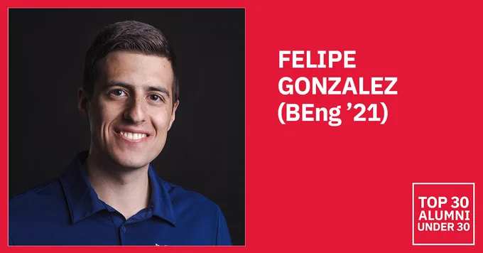 Smiling man in a blue polo shirt against a dark background.
