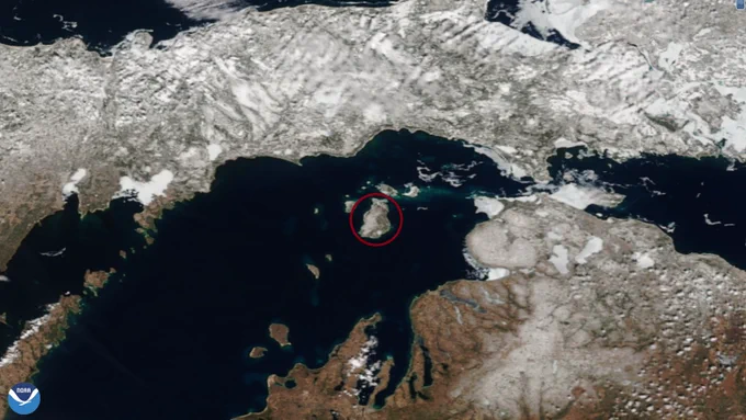 A satellite image of an island with a red circle around it in the middle of a lake with the NOAA logo in the bottom left hand corner.