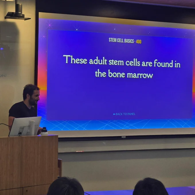 A person is presenting a slide in a lecture room. The slide title is "Stem Cell Basics: 400" and it reads, "These adult stem cells are found in the bone marrow."
