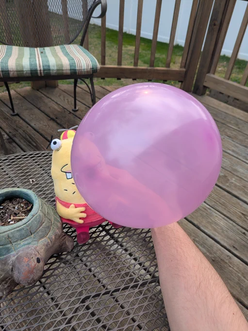 A Beans plushie blowing a giant bubble-gum bubble represented by a ballon.