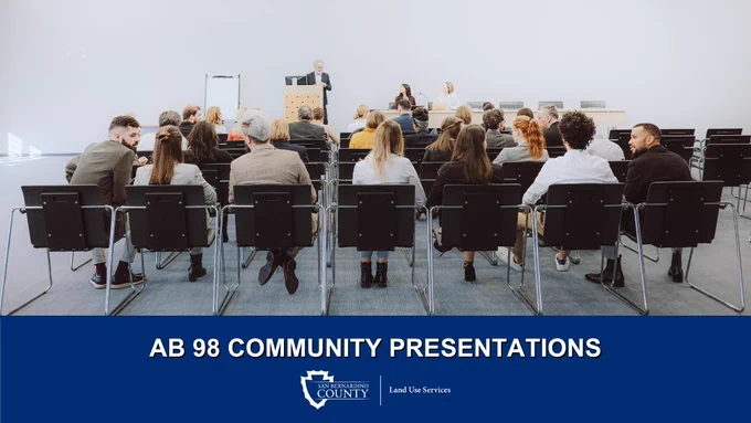 A group of people seated in a conference room facing a speaker at a podium. The presentation is titled "AB 98 Community Presentations" and is hosted by San Bernardino County Land Use Services.