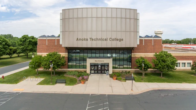 Front view of Anoka Technical College, featuring a brick and cream-colored facade with large windows. 