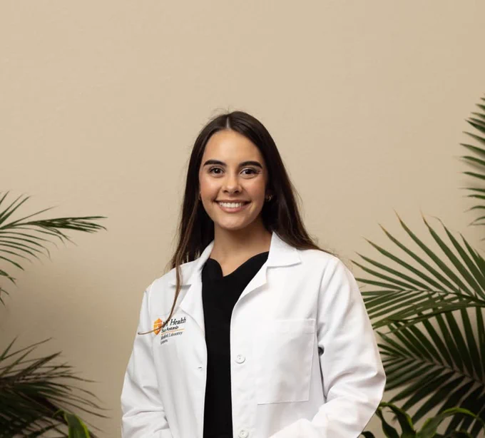 A Texas A&M University-Corpus Christi alumnus poses for a photo in a medical white coat. 