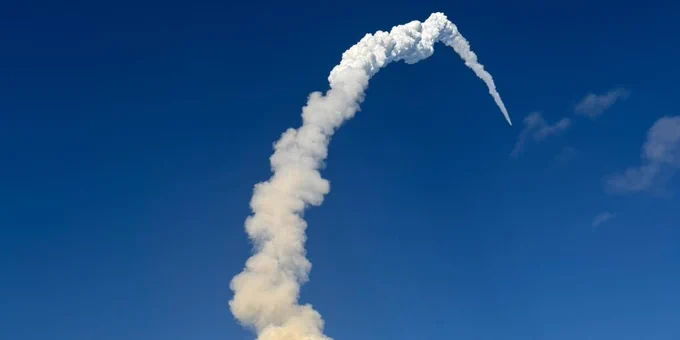 A spaceship taking off with a large exhaust cloud behind it.