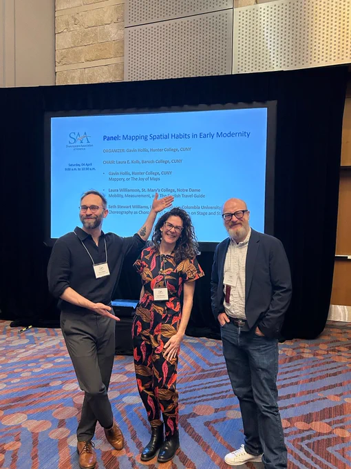 Image of three academics standing in front of a projection screen advertising the Mapping Spatial Habits panel. End ID.