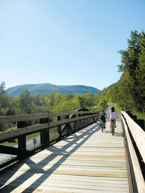 A pair of cyclists cross an converted railroad bridge along the Pine Creek Rail Trail
