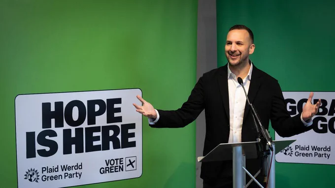 Zack in front of a sign saying Hope is Here
