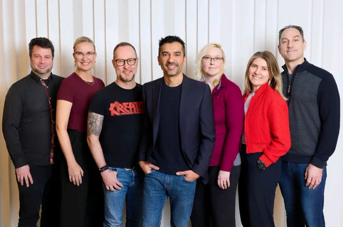 Patrice Baig (center, in the navy blazer)  Eidos-Montréal's new General Manager, pictured part of a group of 8 Eidos-Montréal professionals.