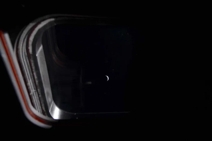 Looking through one of the four windows of the Orion spacecraft, a crescent Earth is illuminated against the blackness of space and grows smaller as the crew journeys closer to the Moon. This image was taken by an Artemis II crew member on the fifth day of the mission.
