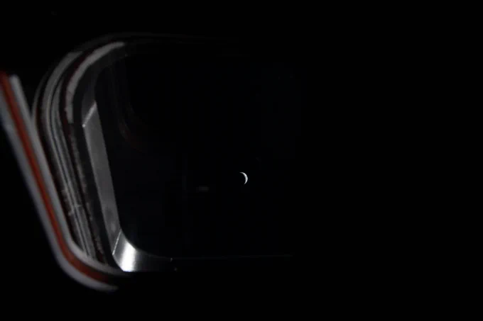 Peering out one of the four windows near the display console on the Orion spacecraft, the Earth is illuminated by the blackness of space and grows smaller as the crew journeys closer to the Moon. This image was taken by an Artemis II crew member on the fourth day of the mission. Credit: NASA