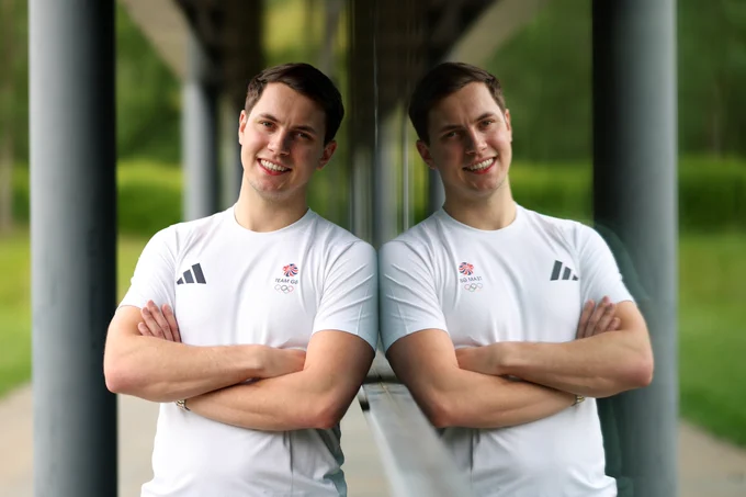 Luke leaning against a mirrored wall in a white Team GB top