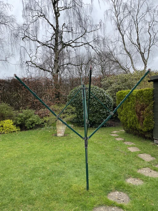 Green four armed rotary airer in a garden with no cord