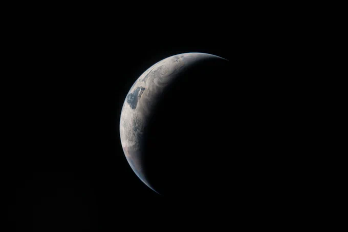 A thin arc glowing in the darkness of space. Sunlight traces the curves of the ocean and clouds, while the rest of the planet fades into shadow. \u00A0Credit: NASA