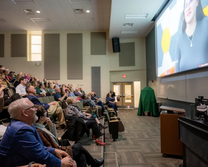Dean Scott Titsworth, front, can be seen smiling up at a video screen, while others watch behind him.