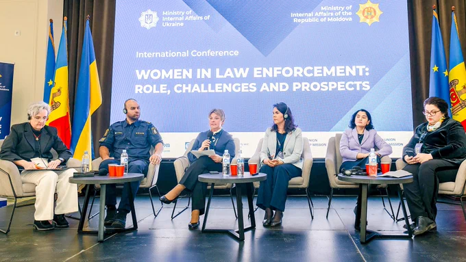 A panel of six individuals sitting on a stage during an international conference titled "Women in Law Enforcement: Role, Challenges and Prospects." They are seated in front of a backdrop featuring logos of the Ministry of Internal Affairs of Ukraine and the Ministry of Internal Affairs of the Republic of Moldova. 