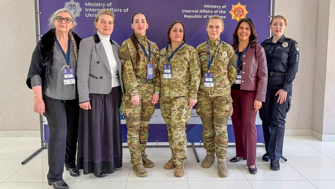 A group of individuals in both military and civilian attire stand in front of a backdrop displaying logos and text for the Ministry of Internal Affairs of Ukraine and the Ministry of Internal Affairs of the Republic of Moldova. They have official identity badges and are arranged in a line, posing for the photo.