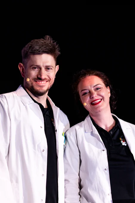 Piotr Przybył and Marit van Dijk smiling at the photographer. Both are wearing lab coats on top of their Java Champion polos.