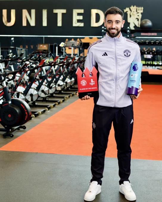 Bruno Fernandes holding up both of his Player of the Month awards at Carrington. 