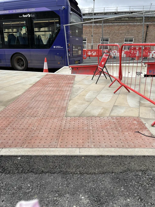 Red tactile paving stretching to the carriageway confusingly indicating a crossing point where there isn’t one
