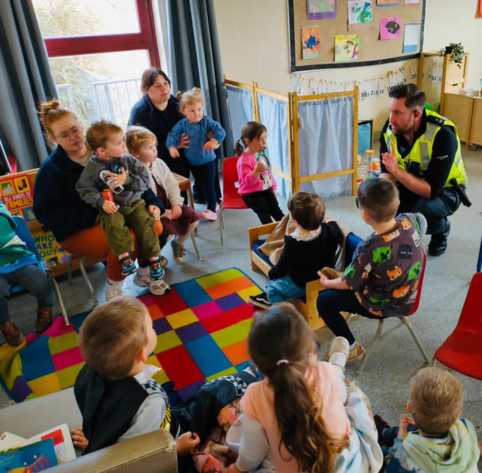 A police officer sitting speaking to school children