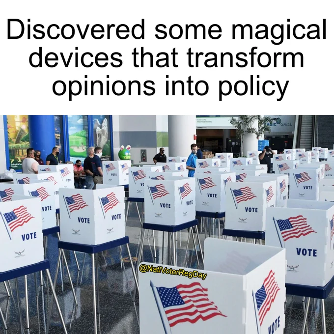 Rows of voting booths with American flags set up in a spacious hall where people prepare to cast ballots.