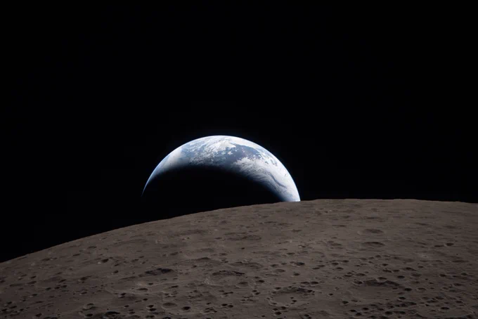 On a black background of space, a blue and white Earth just before 'setting' behind the Moon, in foreground, seen from Artemis II, 6 April 2026