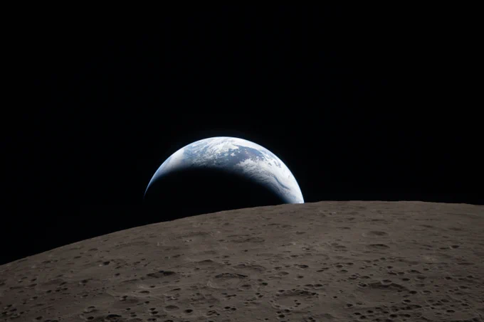 A crescent Earth setting behind the Moon\u2019s horizon. Credit: NASA